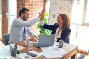 Zwei Mitarbeitende feiern die erfolgreiche Einführung des MehrWertPlan im Büro mit einem High Five.