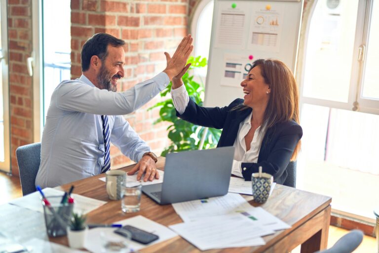 Zwei Mitarbeitende feiern die erfolgreiche Einführung des MehrWertPlan im Büro mit einem High Five.