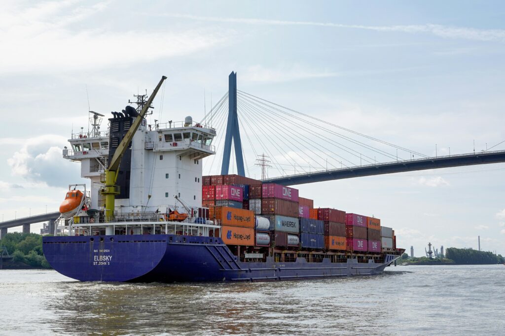 Containerschiff mit Fracht auf der Elbe als Symbol für Spediteur Haftung bei Warenschaden.