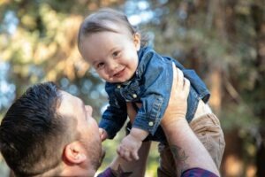 Vater hält sein Baby im Freien auf dem Arm zum Thema bAV in der Elternzeit.
